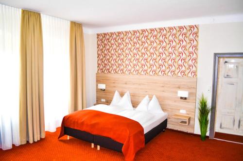 a bedroom with a bed with an orange blanket at Gasthaus-Pension Schwarzer Graf in Windischgarsten
