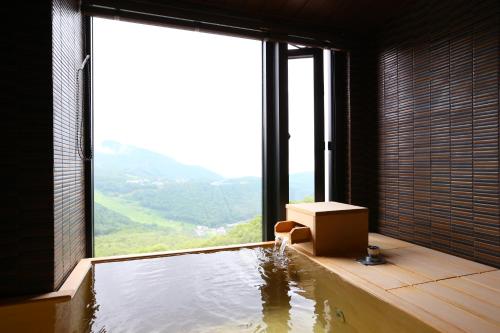 a room with a bath tub with a large window at Hotel Higashidate in Yamanouchi