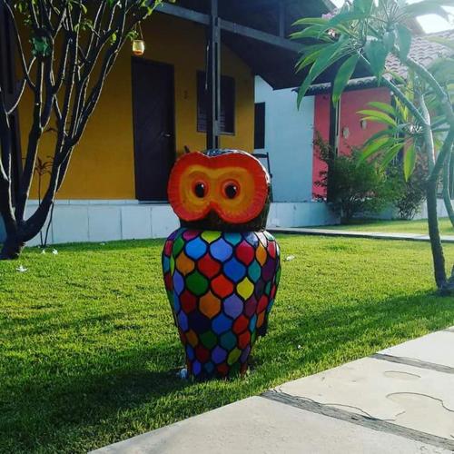 a colorful owl statue sitting in the grass at Chalés do Otto e Karine in Canoa Quebrada