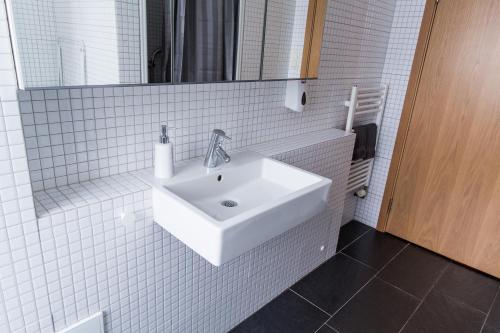a white bathroom with a sink and a mirror at Acco Luxury Apartments in Akureyri