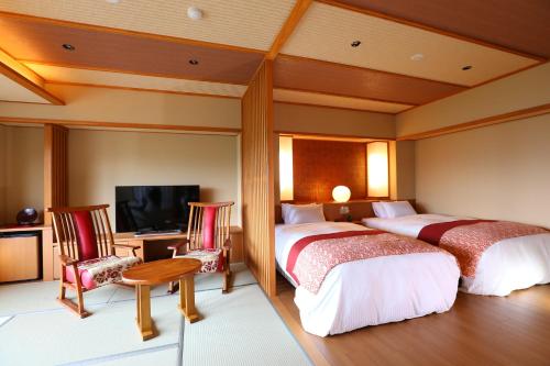 a hotel room with two beds and a television at Hotel Higashidate in Yamanouchi