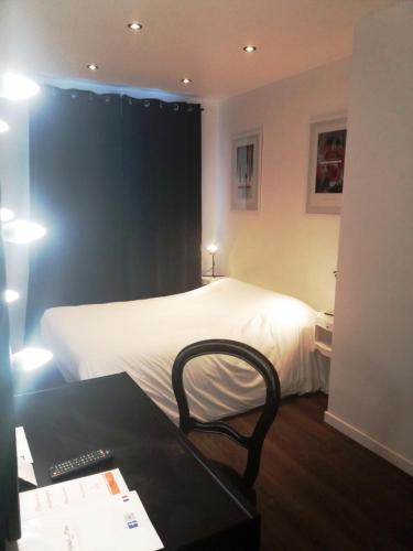 a bedroom with a bed and a desk and a chair at Hôtel De La Paix in Gérardmer