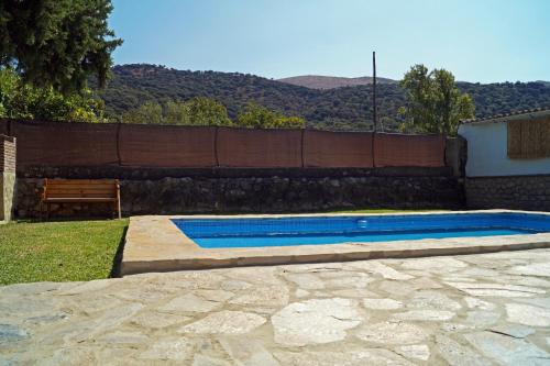 a swimming pool with a bench next to a fence at Casa Rural Los Cipreses in Benaoján