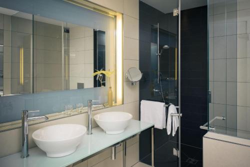 a bathroom with two sinks and a mirror at Vienna House by Wyndham Andel's Berlin in Berlin