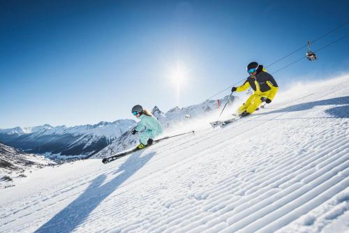two people are skiing down a snow covered slope at Alpenromantik-Hotel Wirlerhof in Galtür
