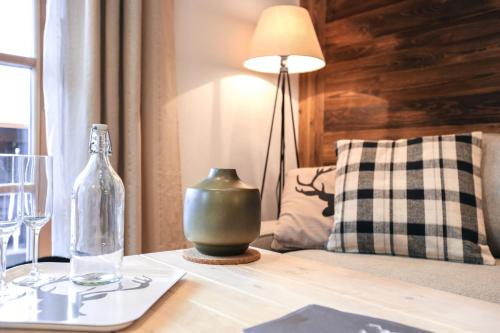 einen Tisch mit einer Glasflasche und einer Lampe darauf in der Unterkunft Steinberghaus Apartments in Leogang