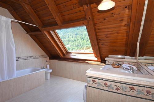 een badkamer met een bad, een wastafel en een raam bij RVHotels Orri in Tredós