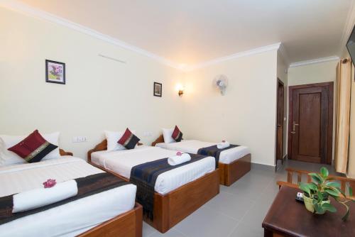a hotel room with three beds and a table at Chamraoen’s Home in Siem Reap