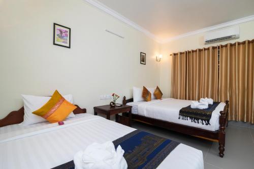a hotel room with two beds and a window at Chamraoen’s Home in Siem Reap