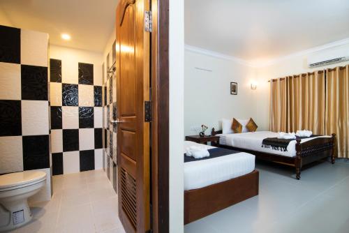 a hotel room with two beds and a toilet at Chamraoen’s Home in Siem Reap