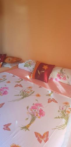 a bed with a flowered blanket with butterflies on it at Guest House Cinderella in Herceg-Novi