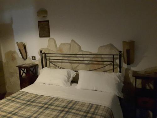 Una cama con sábanas blancas y almohadas en un dormitorio en La Fattoria Di Mamma Ro', en Narni