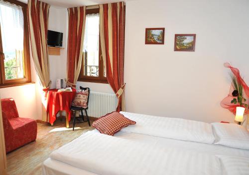a living room with a white bed and a red chair at Albergo Stelvio in Bormio