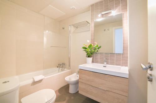 a bathroom with a sink and a toilet and a mirror at Apartamentos Salamanca in Málaga