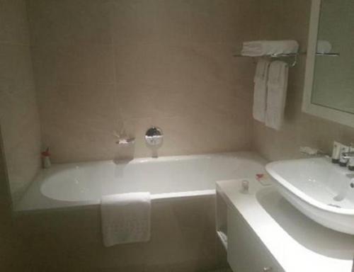 a white bath tub sitting next to a white sink at The Wheatbaker in Lagos