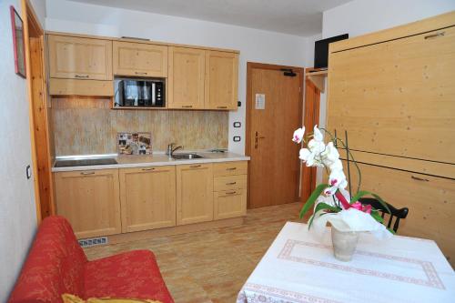 a kitchen with wooden cabinets and a table with flowers at Albergo Stelvio in Bormio