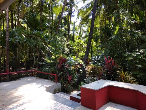 a red bench in a garden with palm trees at Nivaant @ Vicharays in Alibaug