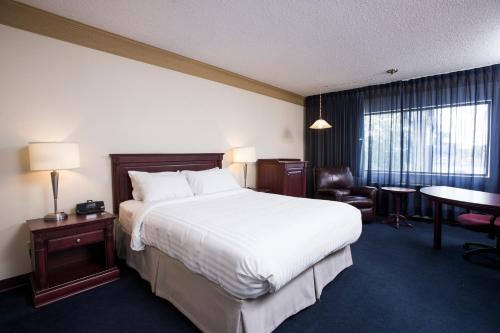 Cette chambre comprend un grand lit et un bureau. dans l'établissement Le Deville par G5, à Rouyn-Noranda