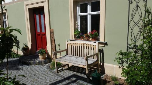 a wooden bench in front of a house with a red door at Luisenhof in Geisfeld