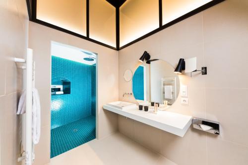 a bathroom with a shower and two sinks and a mirror at Hôtel Du Dragon in Strasbourg