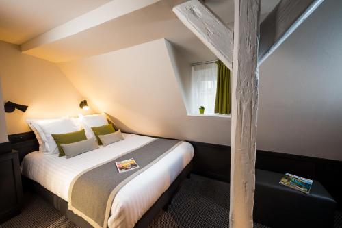 a bedroom with a large bed with a wooden pole at Hôtel Du Dragon in Strasbourg