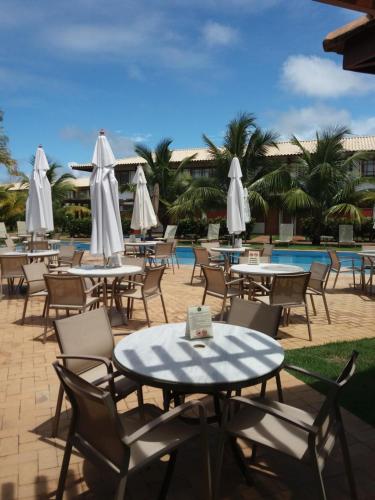 Casa Reserva Praia do Forte في برايا دو فورتي: مجموعة طاولات وكراسي بمظلات بيضاء