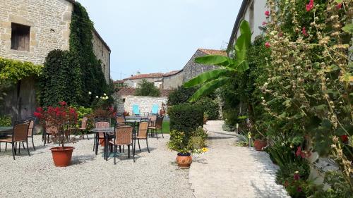 a patio with tables and chairs and plants and flowers at Hôtel du Donjon in Aulnay