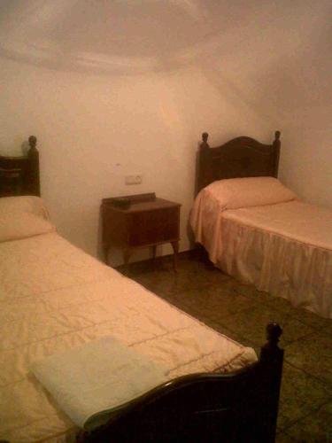 a bedroom with two beds and a nightstand between them at Hostal Medina in Olvera