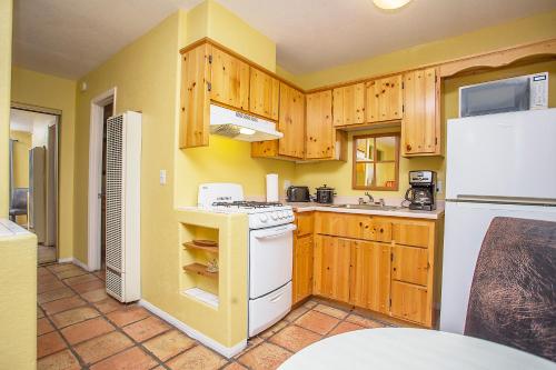 a kitchen with wooden cabinets and a white stove top oven at My Place Suites in Wickenburg