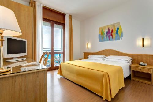 um quarto de hotel com uma cama e uma televisão em Hotel Croce Di Malta em Lido di Jesolo