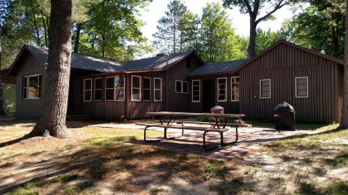 eine Hütte mit einem Picknicktisch davor in der Unterkunft Log Cottage on Blue Lake in Kalkaska