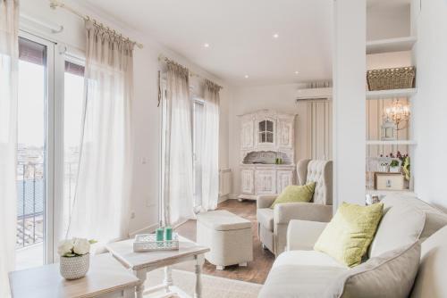 sala de estar con muebles blancos y ventana grande en El Horno de los Bizcochos, en Toledo