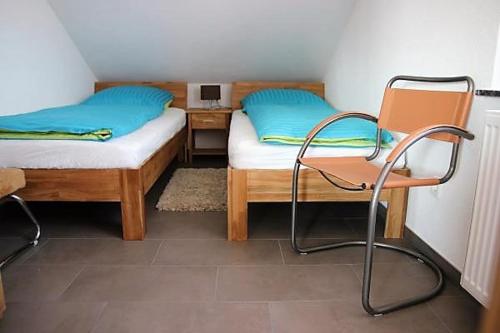 Pokój z 2 łóżkami, krzesłem i biurkiem w obiekcie BodenSEE Apartment Steinackerweg w mieście Meckenbeuren