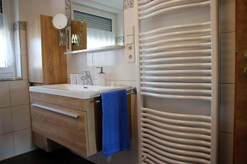 BodenSEE Apartment Steinackerweg في ميكنبورن: حمام مع حوض ومنشفة زرقاء
