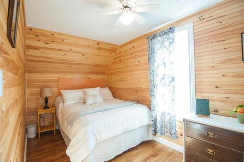 a bedroom with wooden walls and a bed with a window at Cavendish Lodge & Cottages in Cavendish