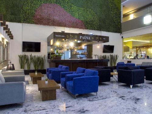 a lobby with blue chairs and a bar at Best Western Plus Santa Cecilia Pachuca in Pachuca de Soto