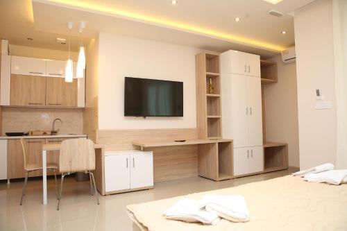 a kitchen with white cabinets and a tv on the wall at Gold Crown Apartments in Jagodina