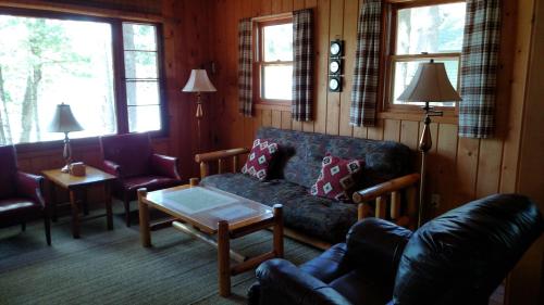 a living room with a couch and a table at Log Cottage on Blue Lake in Kalkaska