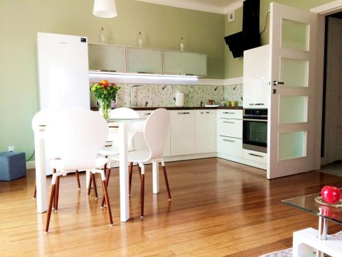 a kitchen with white cabinets and a table and chairs at NEPTUN 46 - 2 sypialnie in Olsztyn