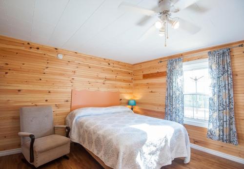 a bedroom with wooden walls and a bed and a chair at Cavendish Lodge & Cottages in Cavendish