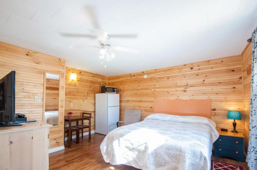 a bedroom with a white bed and wooden walls at Cavendish Lodge & Cottages in Cavendish