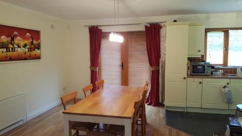 a dining room with a table and a kitchen at Lough Rynn Spacious Self-Catering in Mohill