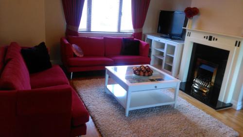 a living room with two red couches and a fireplace at Lough Rynn Spacious Self-Catering in Mohill