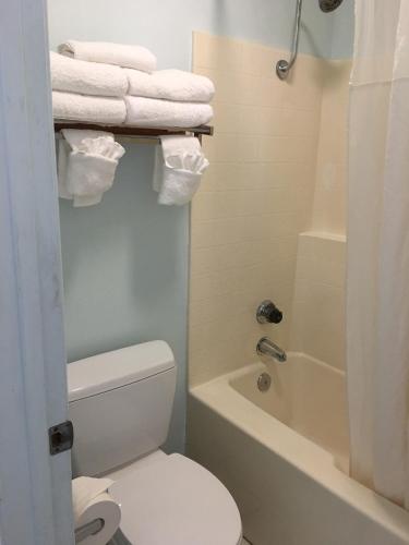 a bathroom with a toilet and a tub and towels at OceanView Motel in Huntington Beach