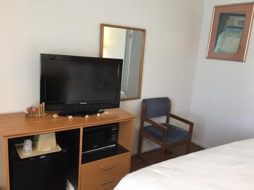 a room with a television on a desk with a chair at OceanView Motel in Huntington Beach