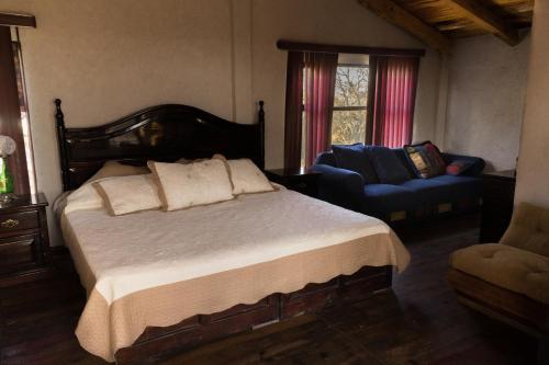 een slaapkamer met een bed, een bank en een stoel bij Rancho los Madroños in Villa del Carbón
