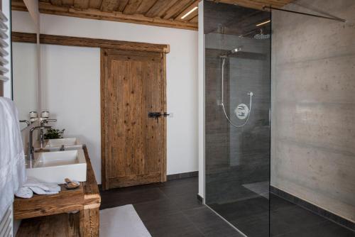 W łazience znajduje się szklana kabina prysznicowa i umywalka. w obiekcie Das Chalet w Schladming