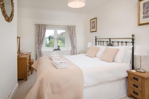 a bedroom with a large white bed and a window at Mona's Cottage in Berwick-Upon-Tweed