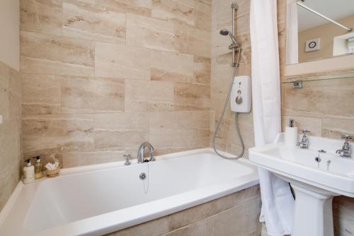 a bathroom with a white tub and a sink at Mona's Cottage in Berwick-Upon-Tweed