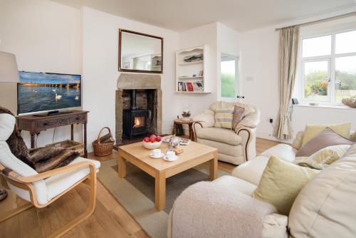 a living room with white furniture and a fireplace at Mona's Cottage in Berwick-Upon-Tweed
